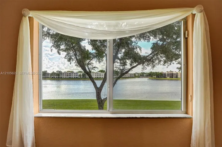 Horizontal sliding window with a stone sill, showcasing exterior water frontage and mature tree scenery