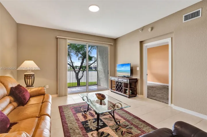 Living area featuring neutral wall paint, tile flooring, and sliding glass doors opening to a private balcony