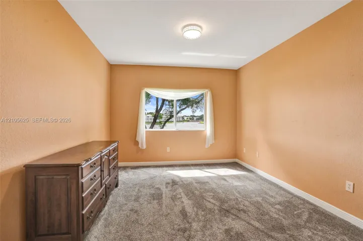 Interior space featuring neutral-toned walls, wall-to-wall carpeting, and a central ceiling-mounted light fixture, finished with a single-pane horizontal window