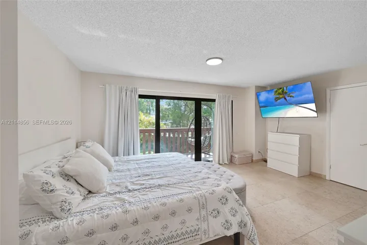 Interior space featuring neutral wall paint, large-format tile flooring, a flush-mount ceiling light, and sliding glass doors with access to an exterior wooden deck