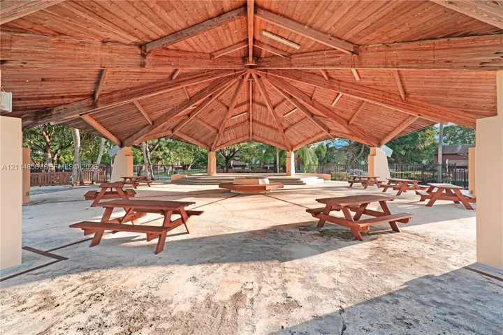 Covered outdoor pavilion featuring a vaulted wood-beam ceiling, concrete flooring, and raised central platform