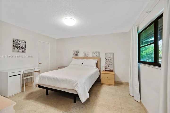 Neutral-toned room featuring stone-finish tile flooring, a large window with black framing, and a central flush-mount ceiling light