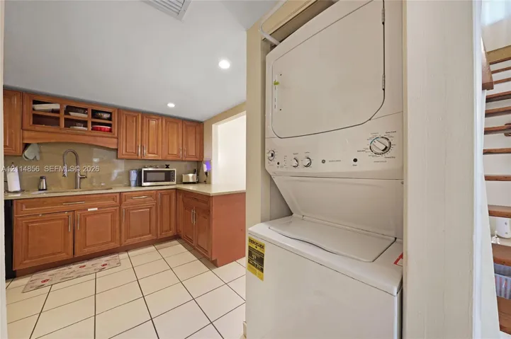 Kitchen featuring wood cabinetry, recessed lighting, tile flooring, and integrated laundry unit