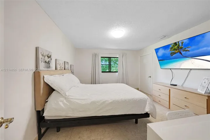 Bedroom featuring neutral walls, wall-to-wall carpeting, and a window with a black frame