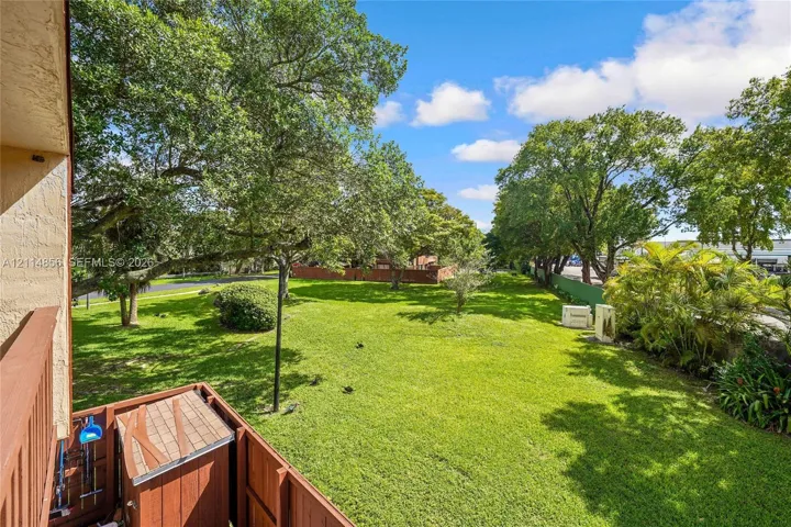 Expansive backyard featuring a manicured lawn, mature trees, and wooden fencing