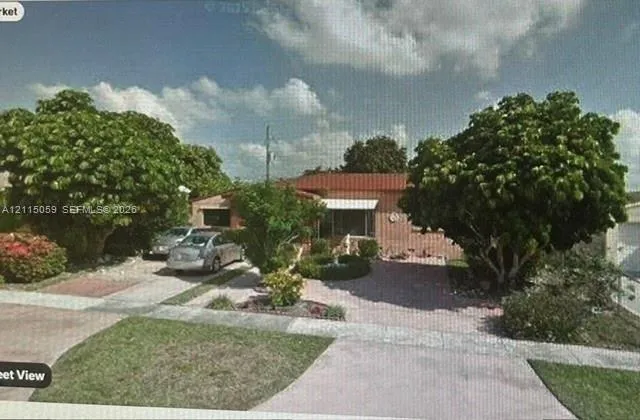 Single-story residence featuring a terracotta-tiled roof, masonry exterior, decorative metal window awnings, and mature landscaping