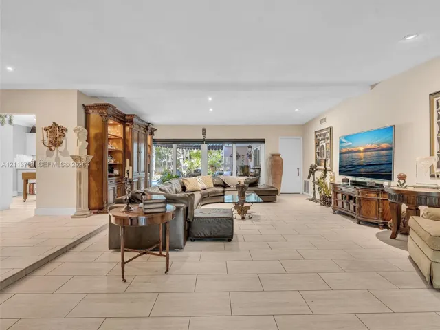 Large living area featuring neutral-tone ceramic tile flooring, recessed lighting, and expansive glass sliding doors
