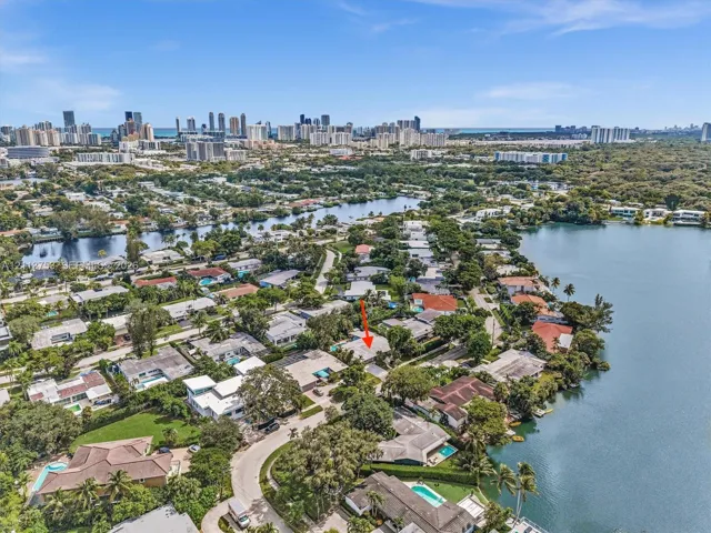 Aerial perspective of a coastal residential area featuring waterfront property proximity, mature canopy trees, and established neighborhood infrastructure