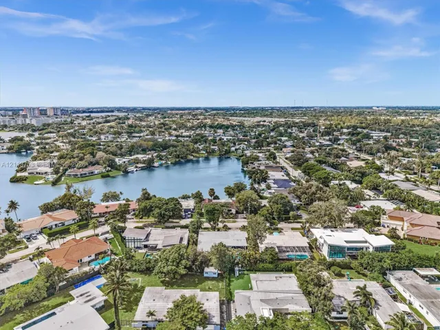 Aerial perspective of residential properties featuring waterfront positioning, expansive tree canopy, and established landscaping