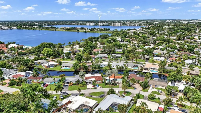 Aerial perspective featuring waterfront placement along a canal with mature landscaping and proximity to a large inland lake