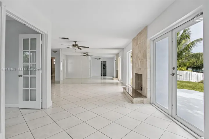Tile flooring, floor-to-ceiling mirrored walls, stone-surround fireplace with a hearth, and glass-paned French doors