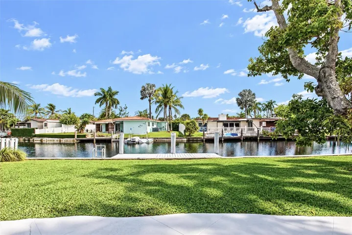 Waterfront lot featuring a manicured lawn, concrete seawall, and private dock
