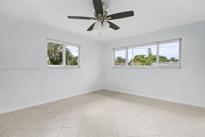 Neutral-toned tile flooring, multi-pane windows, and a ceiling fan with integrated lighting