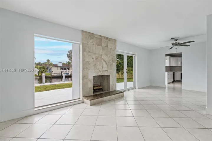 Living area featuring large-format tile flooring, a floor-to-ceiling fireplace with stone tile surround, a built-in stone hearth, and double glass doors