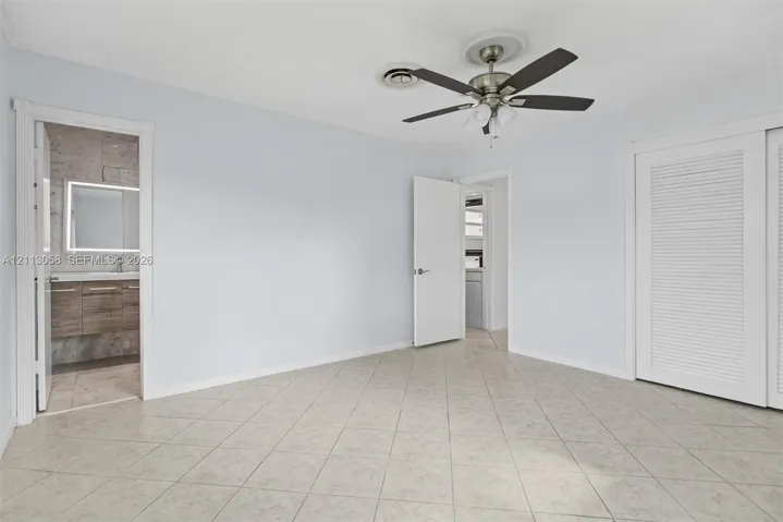 Room featuring tile flooring, ceiling fan with integrated lighting, and dual-door louvered closet