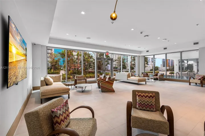 Expansive interior space featuring floor-to-ceiling windows, large-format tile flooring, recessed lighting, and a neutral color palette