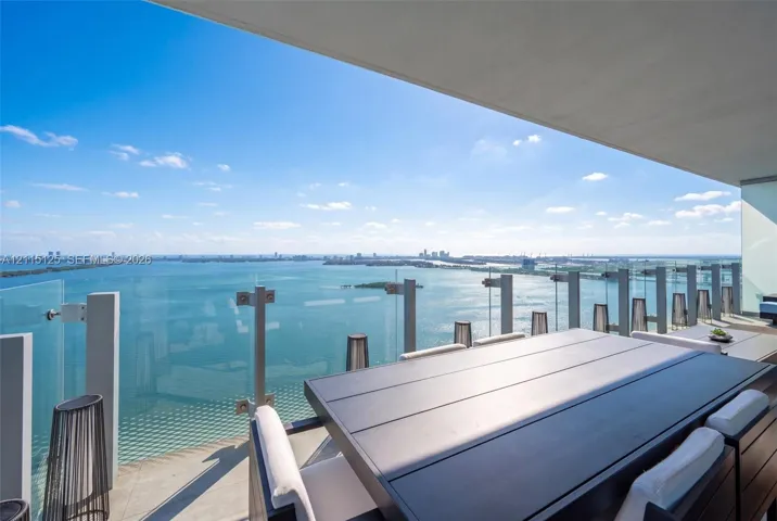 Private balcony featuring large-format tile flooring and frameless glass railing with metallic structural hardware