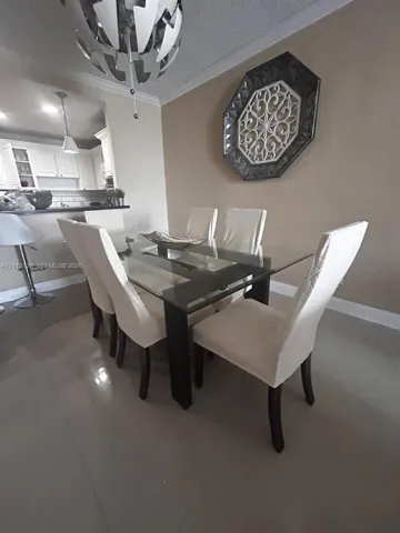 Dining area featuring large-format tile flooring, crown molding, and a contemporary multi-tiered metal chandelier