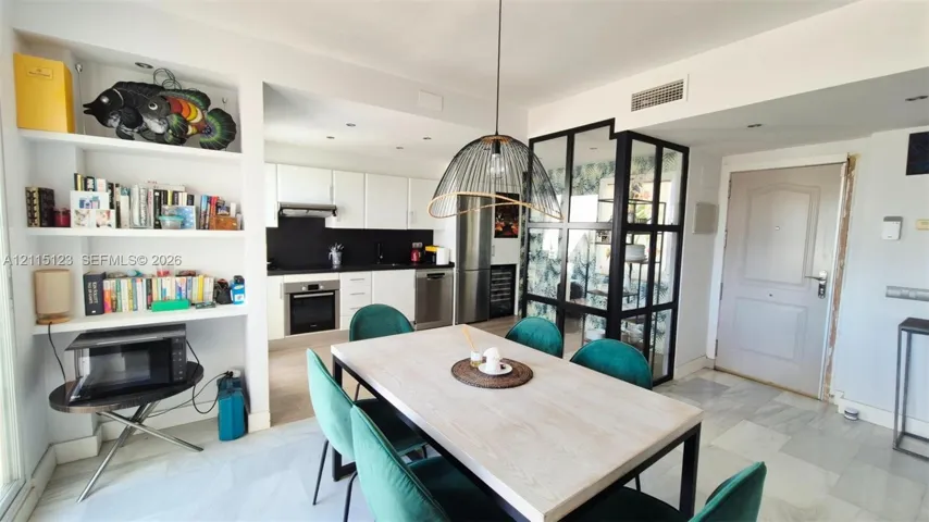 Open-concept kitchen featuring flat-panel cabinetry, a black backsplash, built-in stainless steel appliances, integrated shelving, and stone tile flooring