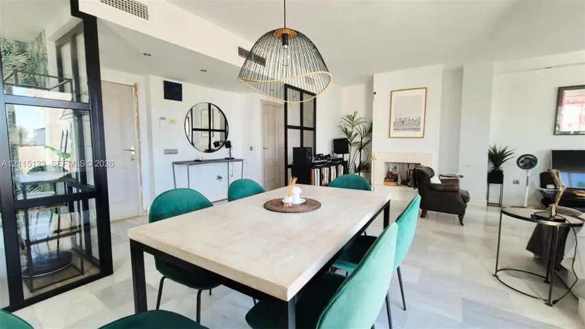 Open-concept living space featuring polished stone flooring, industrial-style black metal room dividers, a recessed fireplace, and a large statement pendant light fixture