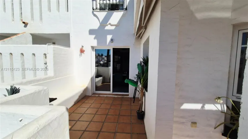Private courtyard featuring terra cotta tile flooring, stucco wall construction, a built-in bench, and a sliding glass door