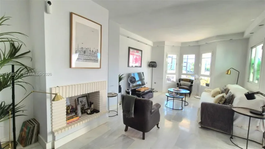 Living area featuring stone-finish flooring, a linear fireplace with a textured masonry surround, recessed ceiling lighting, and a multi-window bay configuration