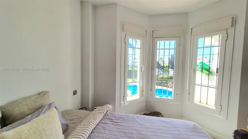 Bay window featuring white frames, integrated security grilles, and roller shutters