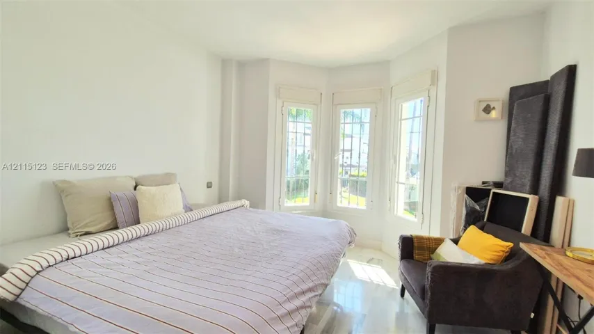 Room featuring a bay window, natural stone flooring, and white interior finishes