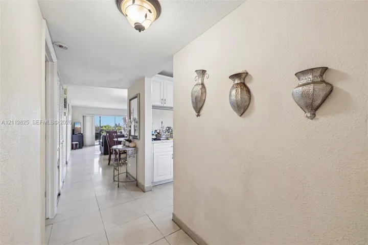 Neutral-toned interior featuring oversized tile flooring, semi-flush mount ceiling lighting, and crisp white cabinetry
