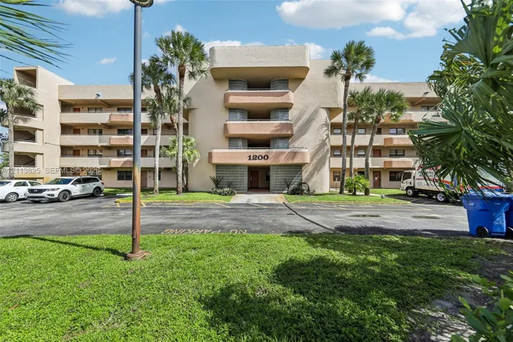 Multi-story exterior featuring a stucco facade, stacked private balconies, glass block accents, and mature palm trees
