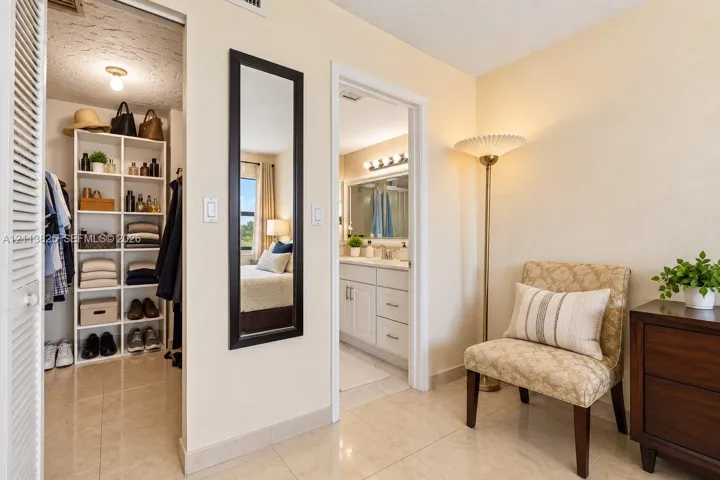 Walk-in closet featuring built-in white shelving, polished tile flooring, and a louvered door