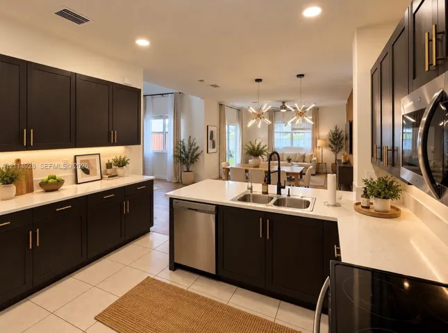 Kitchen featuring dark wood-finish cabinetry with gold-tone hardware, white stone-composite countertops, under-cabinet lighting, a stainless steel undermount sink with a matte black faucet, and recessed ceiling lighting