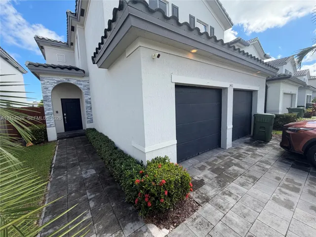 Two-story exterior featuring a stone-accented recessed entryway, paved driveway, and two-car garage with dark-finish doors