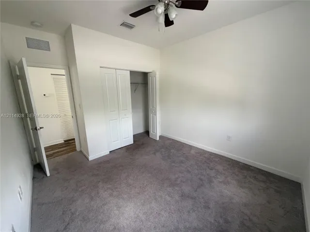 Neutral carpeted flooring, closet with bi-fold doors, and a ceiling-mounted light fixture with a fan