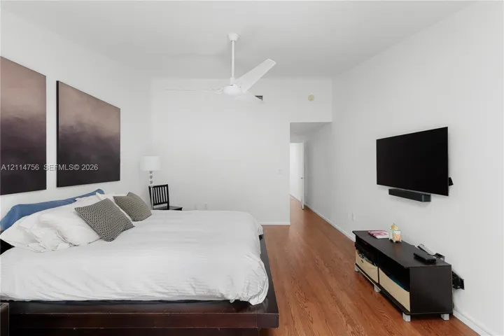 Wood-finish flooring and white ceiling-mounted fan with integrated lighting