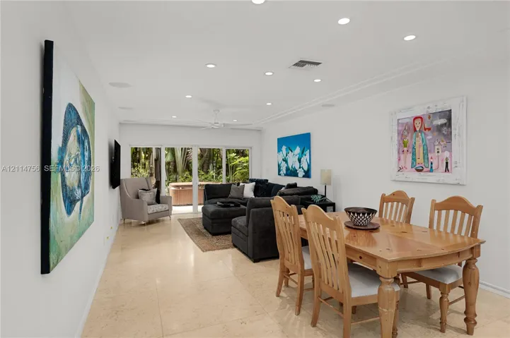 Open-concept interior featuring recessed lighting, smooth finish ceiling, neutral stone-finish tile flooring, and floor-to-ceiling glass sliding doors