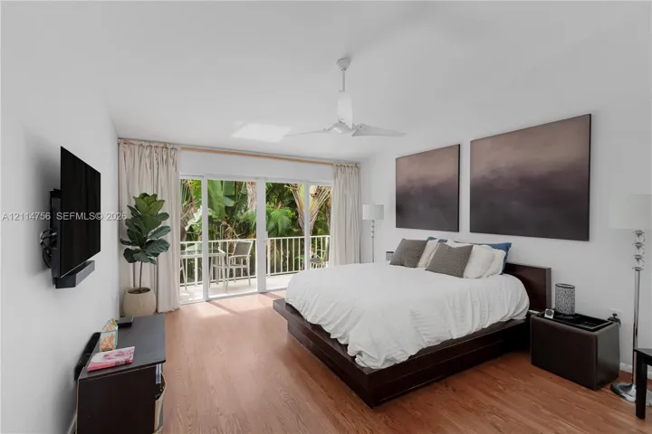 Living space featuring wood-finish flooring, a ceiling fan, and sliding glass doors opening to a balcony