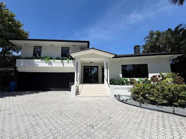 Two-story exterior featuring white stucco finish, geometric paver driveway, recessed lighting, integrated garage, and a covered entryway with concrete steps