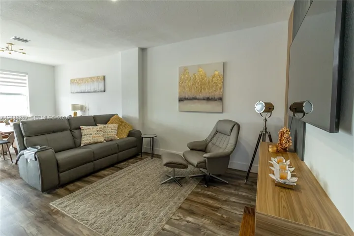 Living area featuring wood-finish flooring, neutral walls, and a wall-mounted television installation