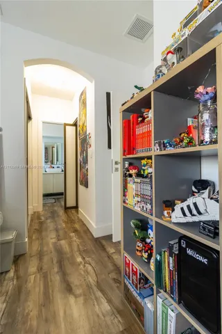 Hallway featuring wood-finish flooring and a prominent arched entryway