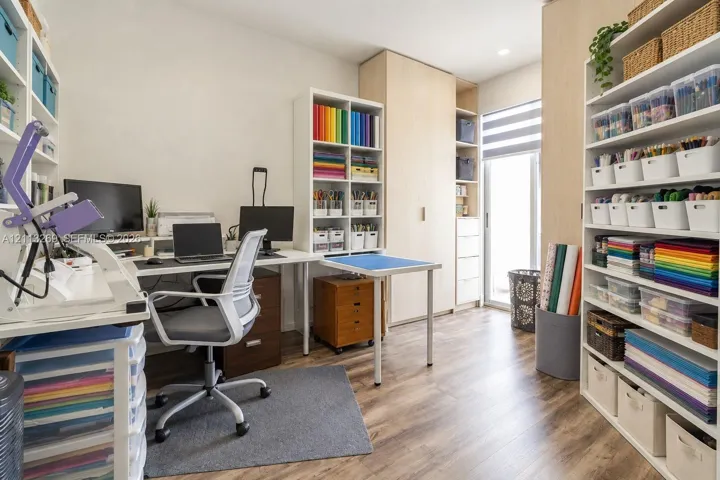 Built-in floor-to-ceiling light-wood cabinetry, wood-finish flooring, and a glass-paneled door with integrated window treatments
