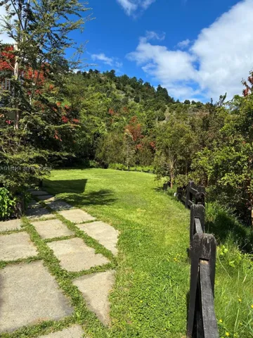 Expansive grounds featuring a grass lawn, stone paver pathway, and dark wood-finish fencing against a mountainous backdrop