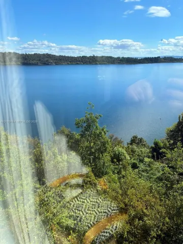 Expansive water frontage featuring mature woodland foliage and a tiered retaining wall