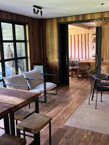 Interior space featuring floor-to-ceiling wood-paneled walls, wood-finish flooring, black-framed windows, and a black-framed sliding doorway