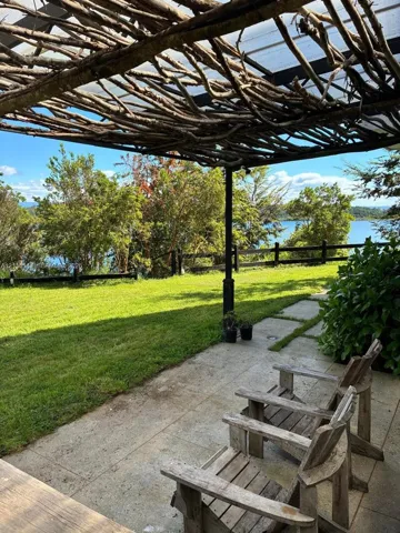 Outdoor patio featuring a custom branch-work pergola, stone-tile flooring, and a fenced lawn area