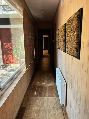 Hallway featuring natural wood-paneled walls, large-format tile flooring, and a expansive glass paneled window