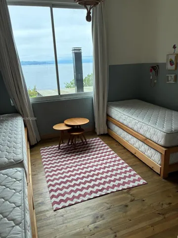 Large windows featuring a water backdrop and wood-finish flooring