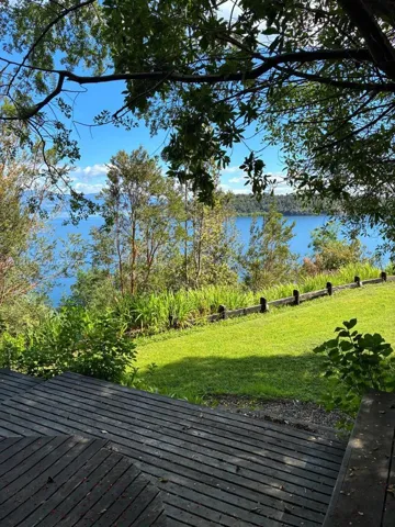 Slatted wood deck overlooking a manicured lawn, tiered landscaping, and a natural water expanse