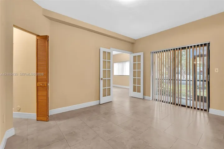 Neutral-tone tile flooring, French doors with glass panes, vertical blinds, and a louvered bi-fold closet door