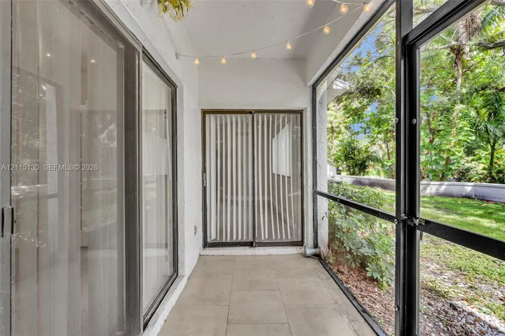 Screened-in patio featuring tile flooring, sliding glass door access, and exterior metal framing